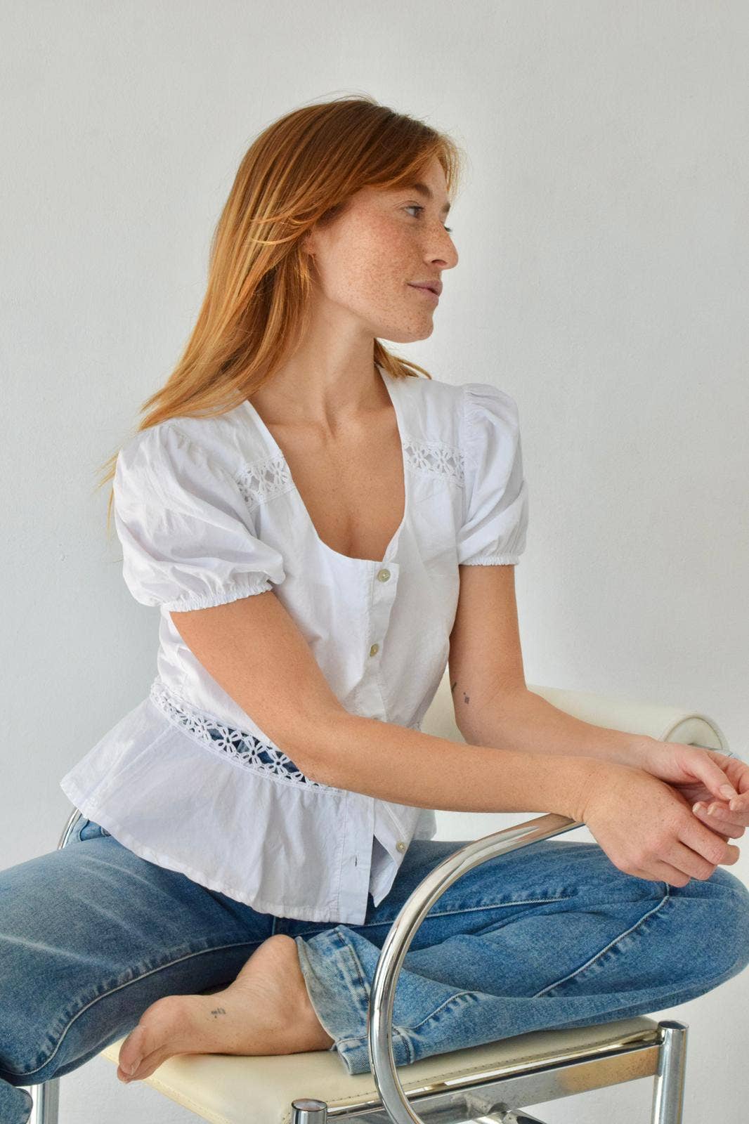 Sittende modell i uanstrengt hvit bluse i poplin med knapper foran og blonder – Vycora Archive