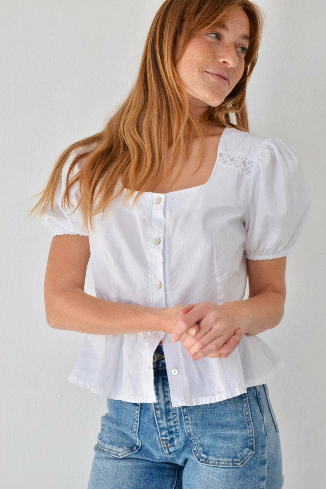 Poserende modell forfra i hvit bluse i poplin med subtil vidde ved falden – Vycora