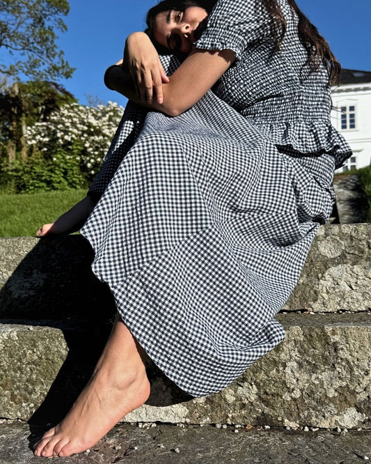 Modell i park som poserer i vidt marineblått gingham A-linjeskjørt med smocket midje – Vycora Archive